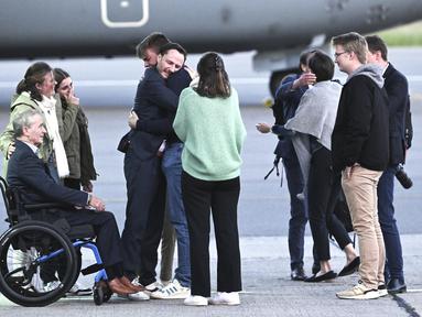Pekerja bantuan Belgia, Olivier Vandecasteele (kiri tengah) disambut oleh keluarganya di landasan ketika dia turun dari pesawat militer Belgia di bandara militer Melsbroek di Melsbroek, Belgia, Jumat (26/5/2023). (Didier Lebrun/Pool Photo via AP)