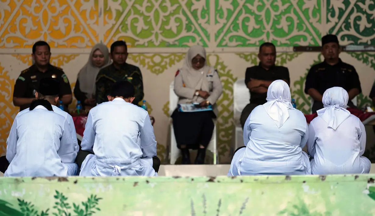 Orang-orang yang dinyatakan bersalah melanggar hukum Islam, di antaranya pasangan yang belum menikah yang terbukti berciuman saat siaran langsung TikTok, menunggu giliran untuk dicambuk di depan umum di Taman Bustanussalatin, Banda Aceh, Aceh, Kamis (2/7/2026). (AP Photo/Reza Saifullah)