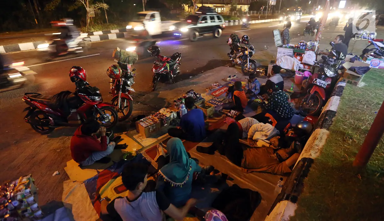 Pemudik menyempatkan beristirahat di pinggir jalan Kota Cirebon karena kelelahan berkendara dari Jakarta, Jumat (24/6). Mereka beristirahat sambil mendinginkan kendaraan bermotor. (Liputan6/JohanTallo)