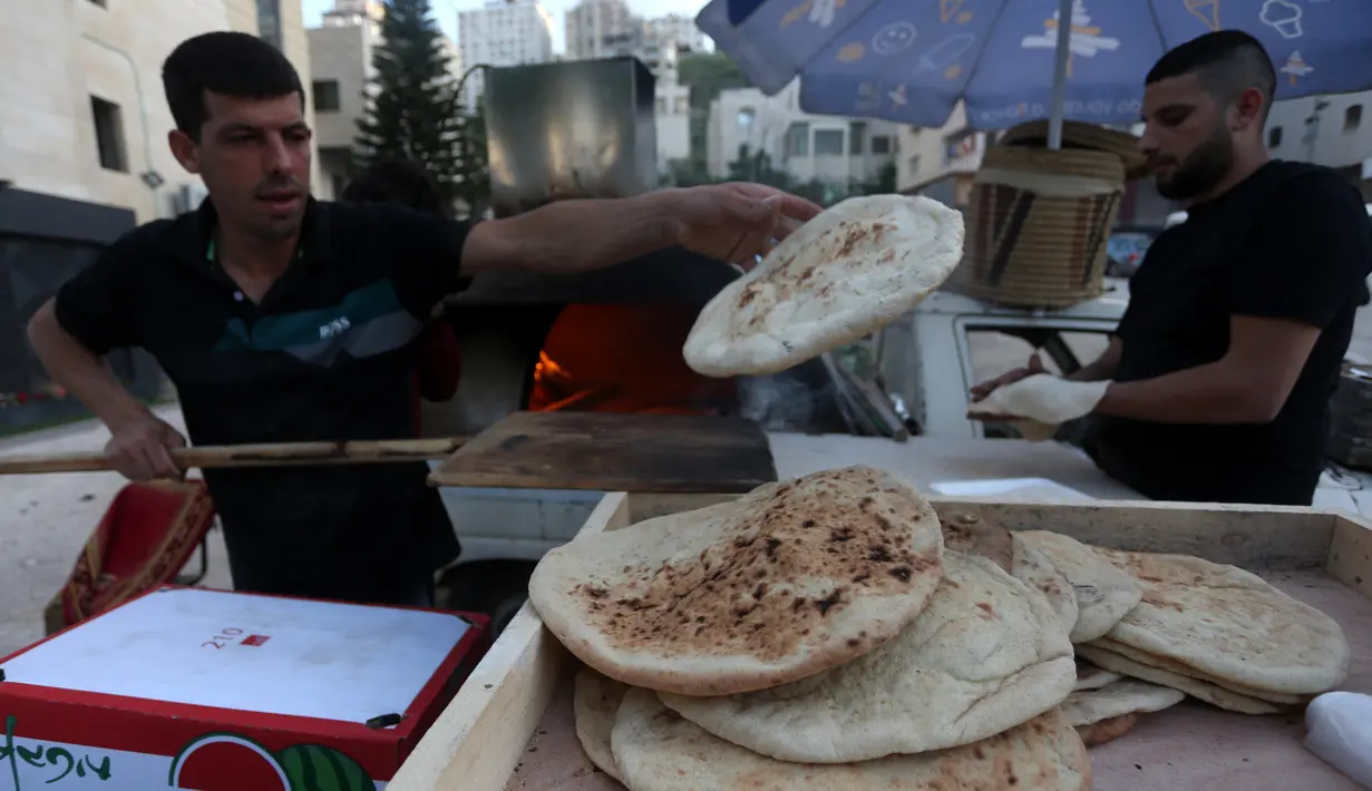 Penjual roti Palestina Mohammed Abu Saud (kiri) menyiapkan roti di Kota Nablus, Tepi Barat, (3/5/2020). Abu Saud, yang kehilangan pekerjaannya sebagai pekerja transportasi karena kebijakan lockdown selama pandemi COVID-19, memutuskan bekerja sebagai penjual roti keliling. (Xinhua/Ayman Nobani)