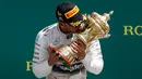 Pembalap Formula 1 tim Mercedes, Lewis Hamilton mencium piala yang diraihnya usai menjuarai Grand Prix Formula 1 Silverstone di Inggris, (5/7/2015). Hamilton berhasil finish di urutan pertama dengan waktu 1 jam 31 menit 27,729 detik. (Reuters/Phil Noble)