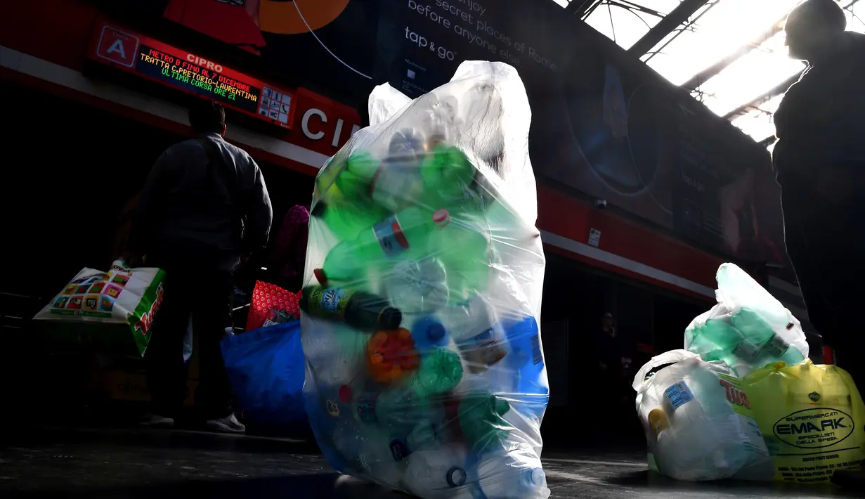 Penumpang antre menukarkan sampah botol plastik dengan tiket kereta menggunakan mesin daur ulang di stasiun metro bawah tanah Cipro, Roma, Selasa (8/10/2019). Warga harus memasang aplikasi di ponsel untuk mendapatkan barcode tiket elektronik setiap kali menukarkan botol plastik. (Tiziana FABI/AFP)