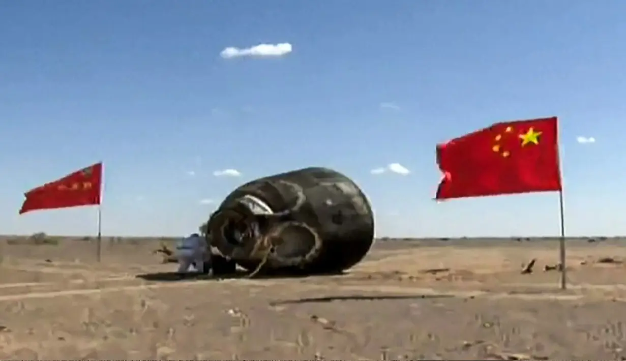 Para pekerja memeriksa kapsul pendaratan setelah mendarat membawa tiga astronot China, Gurun Gobi, 17 September 2021. Trio astronot China kembali ke Bumi setelah 90 hari tinggal di Stasiun Luar Angkasa. (CCTV/AFP)