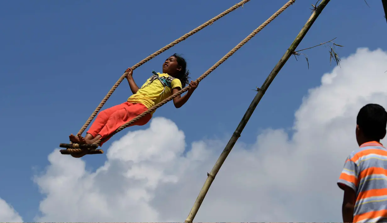 Seorang anak perempuan bermain di ayunan khas negara Nepal di Lalitpur pinggiran kota Kathmandu, Nepal (26/9). Ayunan ini dikenal sebagai 'Dashain Ping' dan dimainkan pada hari keenam festival Hindu Dashain. (AFP Photo/Prakash Mathema)