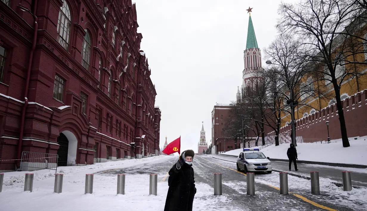 Pendukung komunis tua membawa bendera merah bekas Uni Soviet akan meletakkan bunga di makam pemimpin Soviet Josef Stalin pada peringatan 142 tahun kelahirannya di dekat Tembok Kremlin di Lapangan Merah dengan makam Lenin di kanan di Moskow, Rusia (21/12/2021). (AP Photo/Alexander Zemlanichenko)
