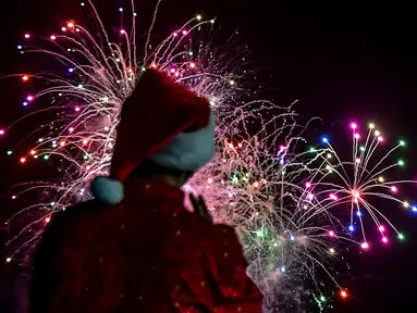 Seorang pria mengenakan kostum santa melihat kembang api selama parade Natal di Panama City (16/12). Warga Panama tengah mempersiapkan diri menyambut datangnya Natal 2018 yang jatuh pada tanggal 25 Desember. (AFP Photo/Luis Acosta)