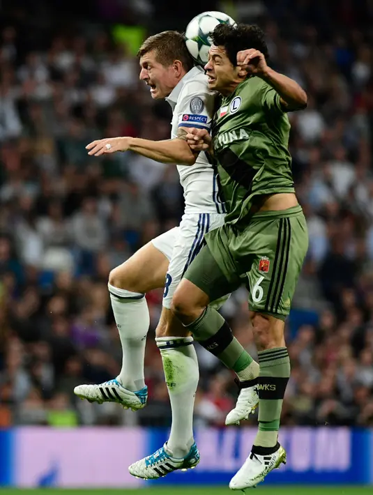 Gelandang Real Madrid, Toni Kroos berebut bola udara dengan gelandang Legia Warsawa, Guilherme Marques pada Liga Champion di stadion Santiago Bernabeu, Spanyol, (18/10). Madrid menang telak atas Legia dengan skor 5-1. (AFP Photo/Pierre-Philippe Marcou)