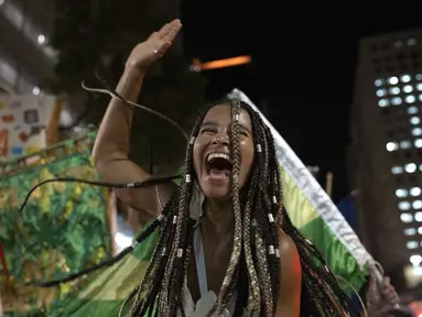 Seorang peserta pesta jalanan yang dikenal sebagai blocos, menari selama protes terhadap pembatasan oleh pejabat kota di Rio de Janeiro, Brasil (13/4/2022). Balai Kota telah melarang pesta jalanan selama perayaan Karnaval, yang tertunda hampir dua bulan karena pandemi. (AP Photo/Silvia Izquierdo)