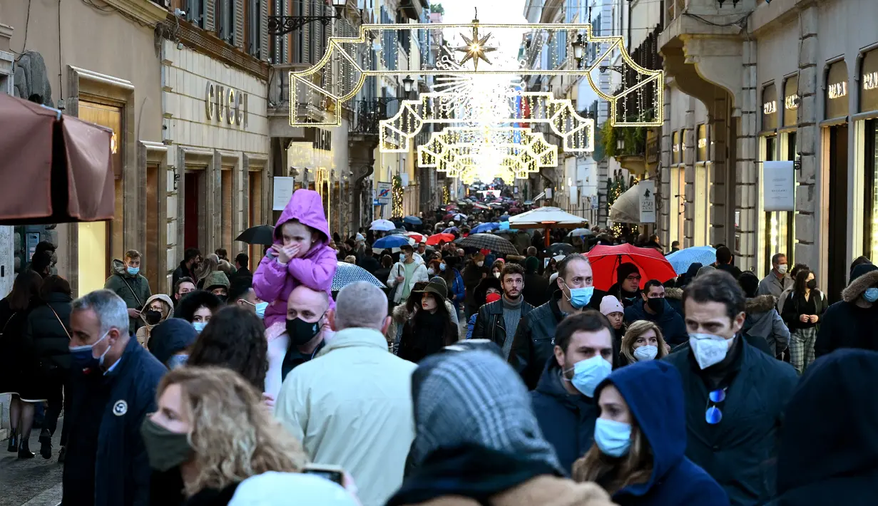 Orang-orang mengenakan masker di sepanjang jalan perbelanjaan mewah Via Condotti di pusat kota Roma, Italia, Minggu (5/12/2021). Kota Roma memberlakukan kewajiban penggunaan masker di ruang terbuka pusat kota dan area perbelanjaan sibuk lainnya hingga 31 Desember mendatang. (Vincenzo PINTO/AFP)