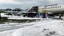Pesawat Sukhoi Superjet-100 milik maskapai Aeroflot dikelilingi oleh busa dari pemadam kebakaran setelah melakukan pendaratan darurat dan terbakar di Bandara Sheremetyevo, Moskow, Rusia, Minggu (5/5/2019). Sedikitnya 41 orang tewas dalam kecelakaan pesawat itu. (Moscow News Agency photo via AP)