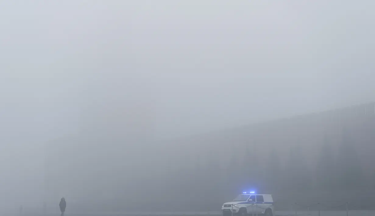 Sebuah mobil polisi diparkir di Lapangan Merah dengan Menara Spasskaya yang tidak terlihat tertutup kabut di Moskow, Rusia, Selasa (2/11/2021).  Kabut tebal menyelimuti ibu kota Rusia pada Selasa, menyebabkan banyak penundaan penerbangan di bandara Moskow. (AP Photo/Pavel Golovkin)
