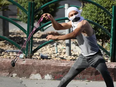 Seorang demonstran Palestina menggunakan katapel untuk melempar batu ke arah tentara Israel saat terjadi bentrokan usai aksi demonstrasi menolak rencana aneksasi Israel di Kota Hebron, Tepi Barat, Jumat (3/7/2020). (Xinhua/Mamoun Wazwaz)