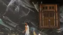Seorang wanita yang mengenakan masker berjalan melewati sebuah mural bertema virus corona COVID-19 selama lockdown di Lodhi Art District, New Delhi, India, Senin (13/4/2020). (SAJJAD HUSSAIN/AFP)