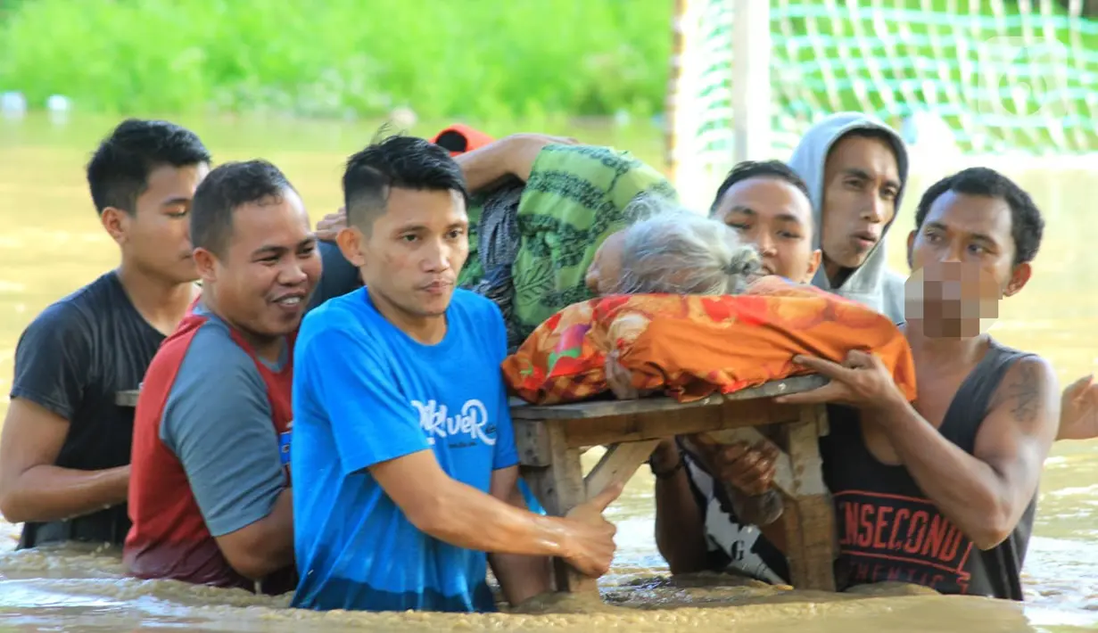 Warga mengevakuasi salah satu orang tua saat banjir bandang  di Kabupaten Bone Bolango, Gorontalo (11/6/2020). Data sementara yang diterima dari BPBD Kabupaten Bone Bolango sekitar 1.078 kepala keluarga serta 5.407 jiwa terdampak banjir bandang. (Liputan.com/Arfandi Ibrahim)