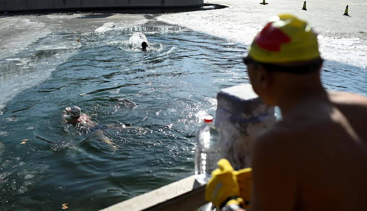 Dua perenang es berenang di danau yang membeku pada hari musim dingin di Beijing (6/1/2021). Berenang di musim dingin adalah kegiatan olahraga yang jarang dijumpai kecuali di beberapa negara dengan musim dingin yang cukup panjang. (AFP/Wang Zhao)
