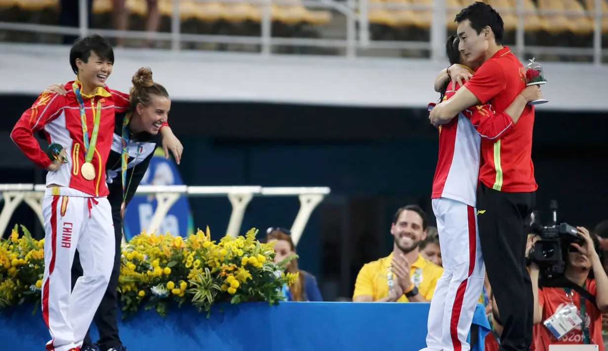Atlet loncat indah asal Italia, Tania Cagnotto dan astlet asal China, Shi Tingmao menyaksikan momen bahagia He Zi saat dipeluk kekasihnya Qin Kai saat lamaran di ajang Olimpiade 2016 di Rio de Janeiro, Brasil, (14/8). (REUTERS/Marcos Brindicci)