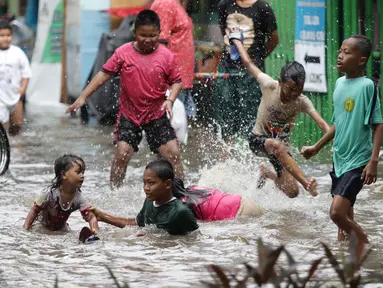 Anak anak bermain air di sebagian Jalan Bungur Besar Raya yang tergenang, Jakarta, Selasa (18/1/2022). Genangan air di sebagian Jalan Bungur Besar Raya dimanfaatkan anak-anak untuk bermain meski berbahaya. (Liputan6.com/Helmi Fithriansyah)
