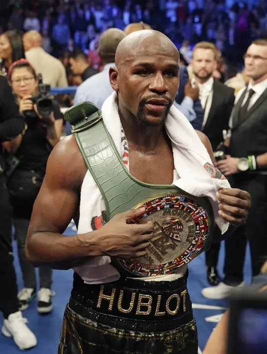 Floyd Mayweather Jr. mengenakan sabuk kemenangan usai mengalahkan Conor McGregor pada gelaran Tinju Dunia super welterweight boxing di MGM Arena, Las Vegas, (26/8/2017). Mayweather menang TKO atas McGregor. (AP/Isaac Brekken)
