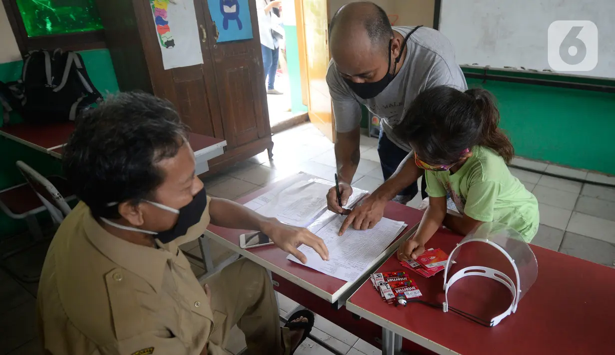 Guru membagikan dua kartu perdana Tri dan Telkomsel beserta kuota gratis kepada wali murid di SDN Serua Indah 1 dan II, Ciputat, Tangerang Selatan, Senin (15/9/2020). Program Kartu Perdana tersebut untuk mendukung kegiatan belajar secara online di masa pandemi covid-19. (merdeka.com/Dwi Narwoko)