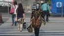 Seorang wanita yang mengenakan baju batik berjalan di kawasan Thamrin Sudirman, Jakarta, Jumat (2/10/2020). Pada Hari Batik Nasional yang berlangsung di tengah pandemi COVID-19, sebagian masyarakat terlihat mengenakan baju dan masker dengan motif batik. (merdeka.com/Imam Buhori)