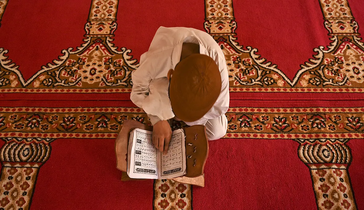 Seorang anak yatim Muslim mengenakan masker bertadarus sambil menjaga jarak sosial di dalam pusat panti asuhan selama bulan suci Ramadan di Srinagar (11/5/2020). (AFP/Tauseff Mustafa)