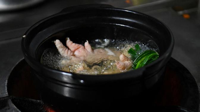 Kaki ayam Dong Tao sedang dimasak di sebuah restoran di Hanoi, Vietnam, 15 Januari 2023. Saat ini para peternak kini telah mengembangbiakkan ayam tersebut untuk dijual pada restoran mahal dan diperuntukan bagi orang kaya. (Nhac NGUYEN/AFP)