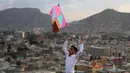 Seorang pria bermain layangan selama perayaan Nowruz di Kabul, (21/3). Meskipun serangan di Kabul menewaskan sedikitnya 29 orang, warga tetap datang di jalanan dengan pakaian berwarna-warni dan terus merayakan Nowruz. (AP Photo/Rahmat Gul)