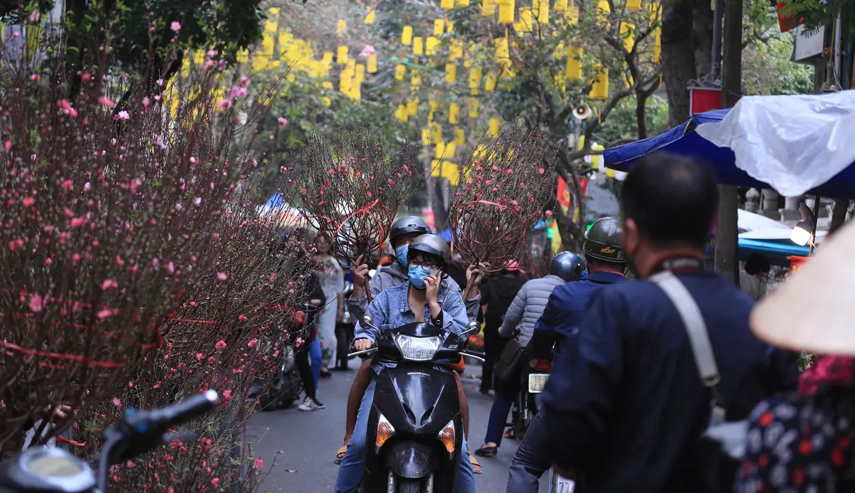 Orang-orang berbelanja bunga persik di pasar "Tet" Tahun Baru Imlek tradisional di kawasan tua Hanoi, Vietnam, Jumat (28/1/2022). Vietnam merayakan Tahun Baru Imlek yang akan datang di tengah peringatan terhadap perjalanan dan pertemuan besar karena COVID -19. (AP Photo/Hau Dinh)