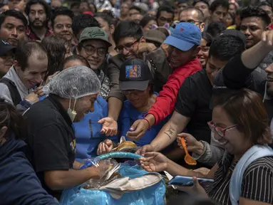 Orang-orang menunggu untuk menerima taco selama acara pemecahan rekor untuk taco terbanyak yang disajikan dalam satu jam - 30.000 - di monumen Angel of Independence di Mexico City, Minggu, 11 Agustus 2024. (AP Photo/Aurea del Rosario)