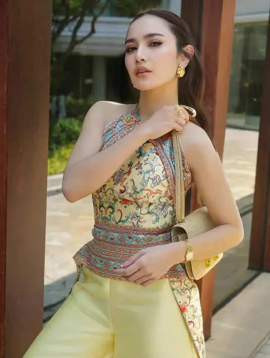 <p>Mahalini mengenakan cheongsam kuning bermotif model halter neck backless, dipadukan celana panjang kuning. Ia juga mengenakan anting-anting kuning tembaga. Sambil membawa tas Hermesnya. [@mahaliniraharja]</p>