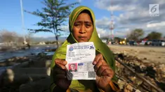 Seorang ibu bernama Lita, menunjukkan foto anaknya, Nanang Kosim (20) yang belum ditemukan pascagempa dan tsunami Palu di Pantai Talise, Sulawesi Tengah, Senin (8/10). Nanang diduga masih tertimbun di dalam tanah saat tsunami. (Liputan6.com/Fery Pradolo)