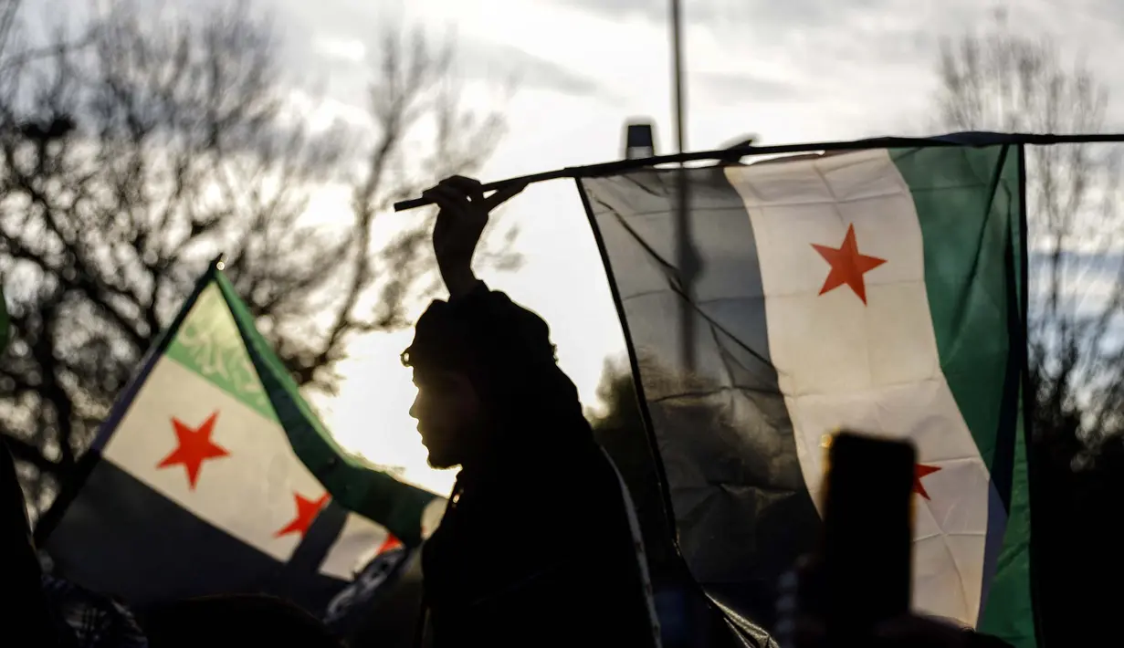 Seorang pria mengibarkan bendera oposisi saat anggota komunitas dan pendukung Suriah berkumpul untuk merayakan kejatuhan Presiden Suriah Bashar al-Assad, di distrik Fatih, Istanbul, 8 Desember 2024. (KEMAL ASLAN/AFP)