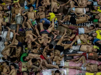 Narapidana tidur di lapangan basket terbuka di penjara Quezon City di Manila, Filipina, 19 Juli 2016. Sejak dibangun enam dekade lalu sudah terdapat 3.800 narapidana yang mendekam dibalik jeruji rutan yang diperuntukan bagi 800 orang itu. (Noel Celis/AFP)