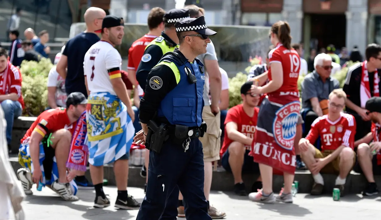 Polisi Spanyol berjaga di tengah suporter Bayern Muenchen Mayor sebelum pertandingan leg kedua perempat final Liga Champions antara Real Madrid dan Bayern Muenchen di stadion Santiago Bernabeu, Spanyol (18/4). (AFP Photo / Gerard Julien)