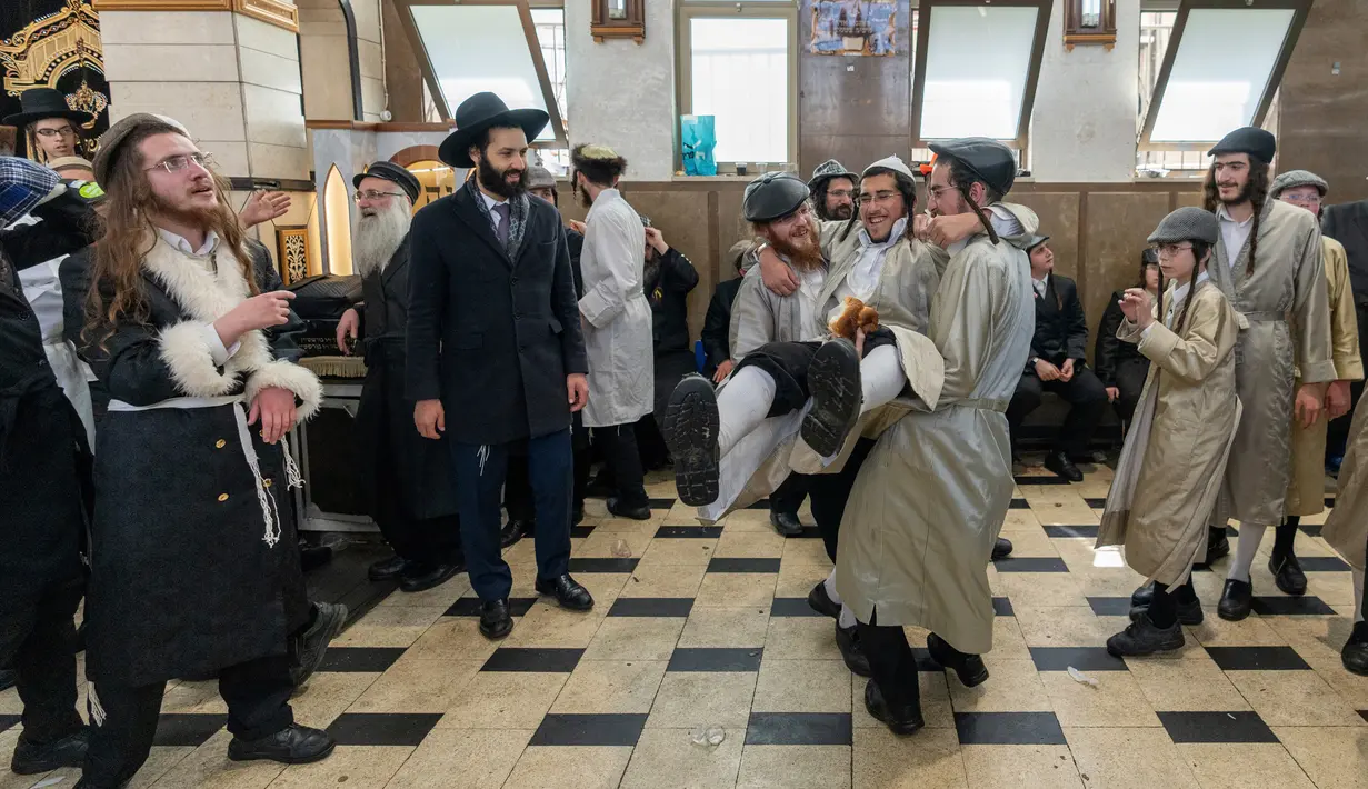 Pria Yahudi ultraortodoks menari selama Festival Purim di lingkungan ultraortodoks Mea Shearim, Yerusalem, 8 Maret 2023. Hari Raya Purim merupakan perayaan keselamatan orang Yahudi dari genosida di Persia kuno, seperti yang diceritakan dalam Gulungan Ester. (AP Photo/Ohad Zwigenberg)