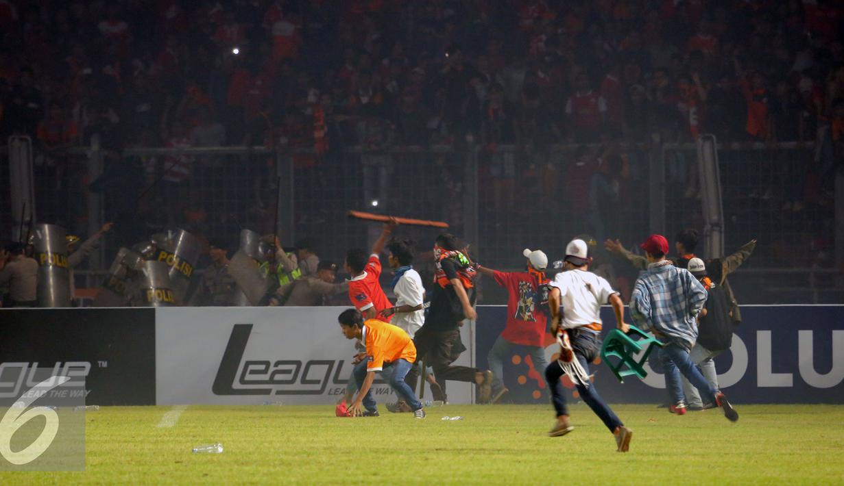 Suporter Persija melempari petugas kepolisian saat terlibat kericuhan pada laga lanjutan Torabika Soccer Championship presented by IM3 Ooredoo antara Persija melawan Sriwijaya FC diStadion GBK Jakarta, Jumat (24/6). (Liputan6.com/Helmi Fithriansyah)
