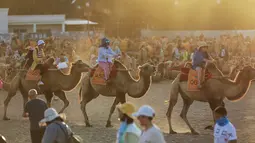 Para wisatawan menaiki unta di padang pasir di Dunhuang di provinsi Gansu di China barat laut (10/8/2019). Unta yang digunakan untuk menjelajahi padang pasir di Dunhuang berbeda dengan yang di Arab Saudi. Unta Mongolia mempunyai dua punuk, sedangkan di Arab hanya satu punuk. (AFP Photo/Str)