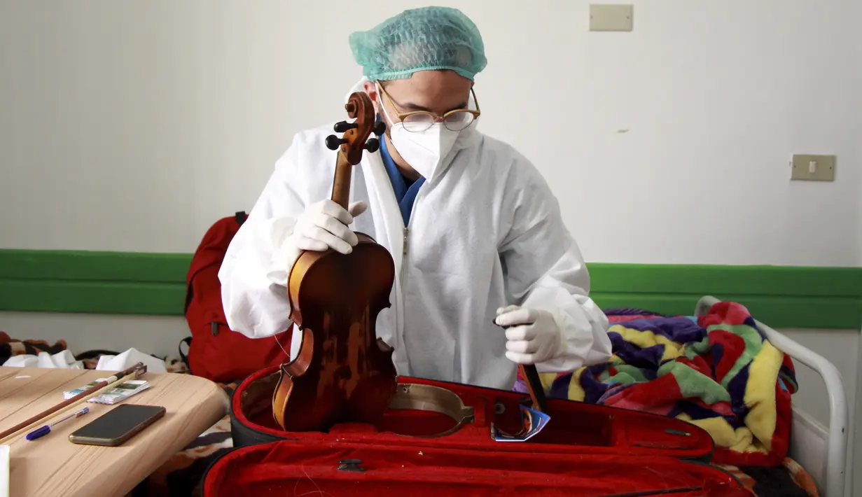 Dr. Mohamed Salah Siala mengeluarkan biolanya untuk menghibur pasien di bangsal COVID-19 rumah sakit Hedi Chaker di Sfax, Tunisia, 20 Februari 2021. Ketika pemain 25 tahun itu memutuskan memainkan biolanya, dia mendapat pujian karena meningkatkan semangat para pasien yang terisolasi. (AP Photo)