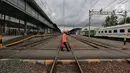 Petugas berjalan menyeberangi rel di Stasiun Pasar Senen, Jumat (24/4/2020). Terkait larangan mudik Lebaran 2020, Stasiun Pasar Senen untuk sementara tidak melayani keberangkatan kereta jarak jauh dari tanggal 24 sampai 30 April 2020 mendatang. (Liputan6.com/Johan Tallo)