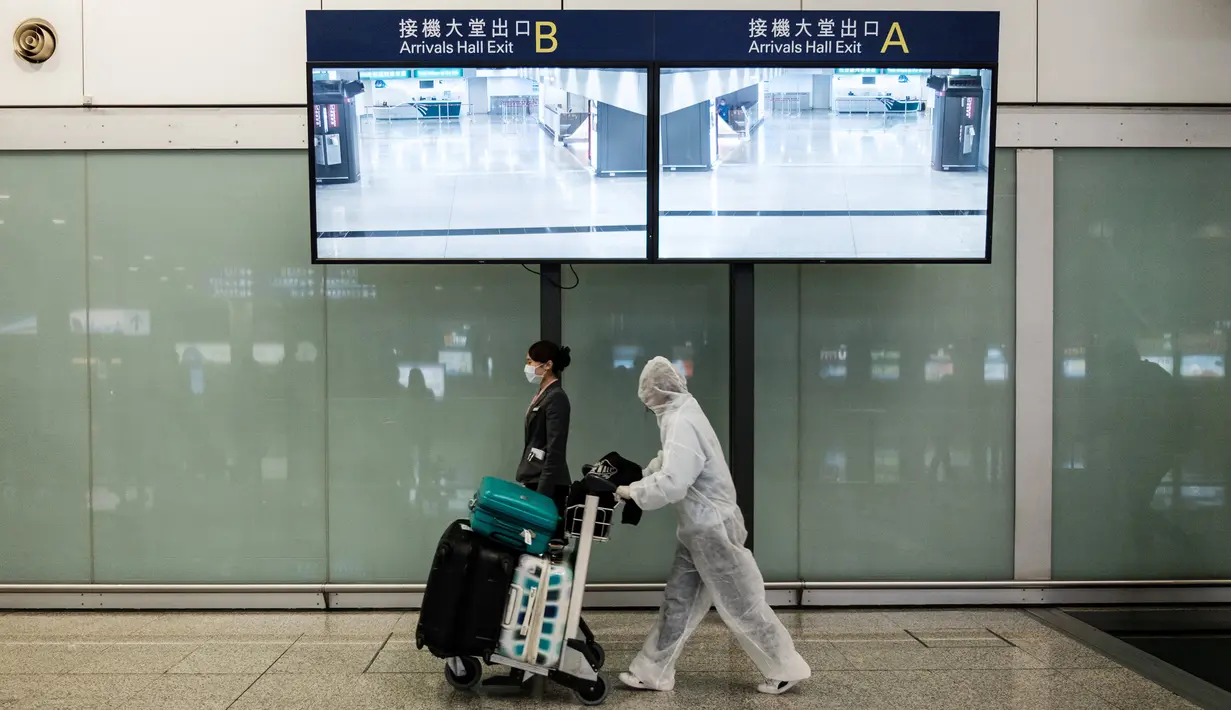 Penumpang mengenakan pakaian pelindung saat tiba di Bandara Internasional Hong Kong, Hong Kong (19/3/2020). Para penumpang di Bandara Hong Kong terpantau memakai perlindungan 'ekstra' lantaran takut tertular virus corona. (AFP/Anthony Wallace)