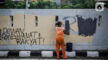 Petugas PPSU membersihkan coretan yang mengotori pembatas jalan pascaunjuk rasa di kawasan DPR/MPR, Jakarta, Jumat (17/7/2020). Coretan tersebut dilakukan oleh massa yang menolak RUU Omnibus Law Cipta Lapangan Kerja di depan Gedung DPR pada Kamis (16/7) kemarin. (Liputan6.com/Faizal Fanani)