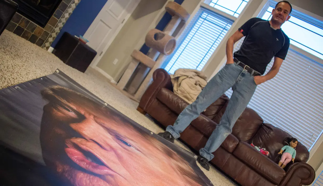 George Davey, pendukung calon Presiden AS Donald Trump melihat poster berukuran besar diruang tamu rumahnya untuk mengantikan poster trump yang pernah dirusak dihalaman belakang rumahnay di West Des Moines, Iowa, (25/1/2016). (AFP/JIM WATSON)