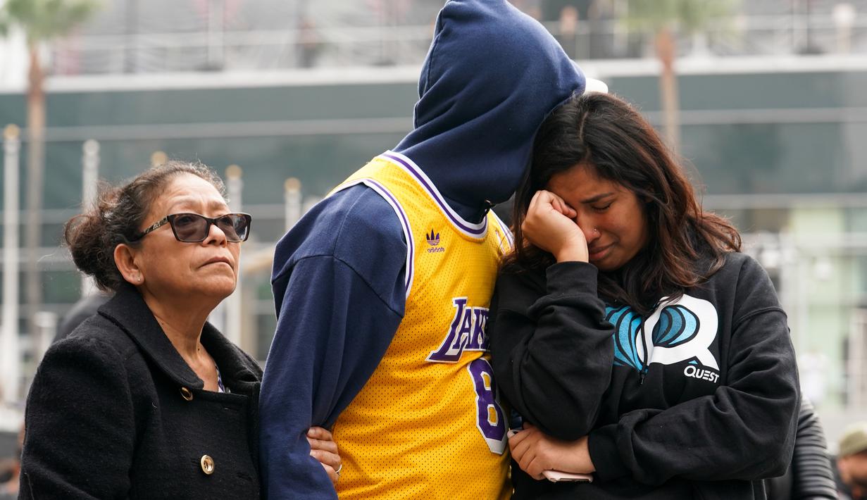Fans LA Lakers tampak sedih usai Kobe Bryant meninggal dunia di Staples Center, Minggu (26/1/2020). Legenda basket NBA itu wafat dalam kecelakaan helikopter di Calabasas, California. (AFP/Rachel Luna)