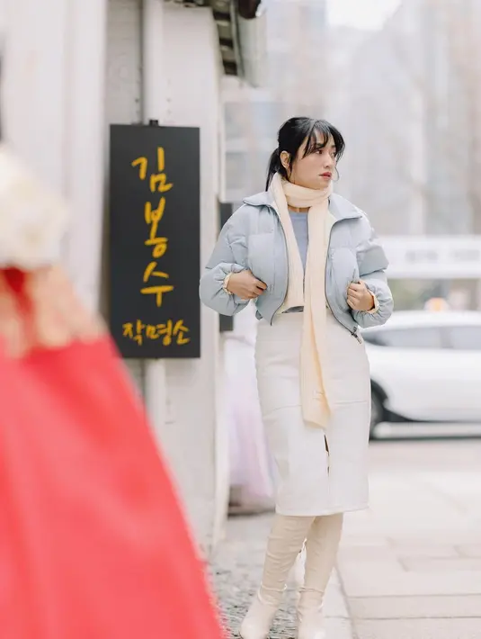 Hesti Purwadinata tampil manis mengenakan inner berwarna biru muda, ditumpuk dengan cropped puffer jacket bernuansa senada. Penampilannya dipadukan dengan midi skirt berwarna putih, dipadu high boots cokelat muda yang serasi dengan syalnya. [Foto: Instagram/hestipurwadinata]