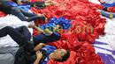 Suporter tertidur usai ikut dalam kegiatan menjahit bendera Merah-Putih raksasa di Tangerang, Sabtu (31/10/2015). Selain ingin mencatat rekor dunia, tema dasar adalah "One Soul, One Nation Untuk Sepakbola Indonesia".  (Bola.com / Nicklas Hanoatubun).