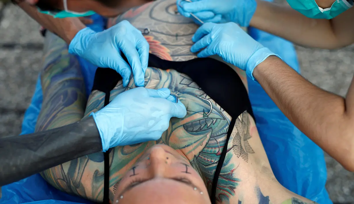Profesional body artist, Dino Helvida dan pacarnya Zorana Unkovic menusukkan 10 mata kail pada tubuh Kaitlin di Zagreb, Kroasia (7/6). Kaitlin terlihat tenang meski sejumlah mata kail tajam menembus kulitnya. (REUTERS/Antonio Bronic)