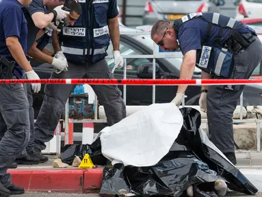 Polisi Israel memeriksa mayat pria Palestina yang ditembak mati usai menikam dua warga Israel di Tel Aviv, Kamis (8/10). Menurut juru bicara polisi Israel, pria Palestina itu menikam tentara wanita dengan obeng di Mulailah Street. (AFP PHOTO/JACK GUEZ)