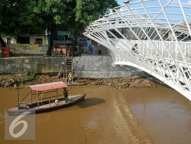 Perahu melintas di bawah Pembangunan jembatan penyeberangan orang (JPO) sungai Ciliwung, Jakarta, Senin (4/4). Rencaanya JPO tersebut siap digunakan pada 6 April mendatang. (Liputan6.com/Yoppy Renato)