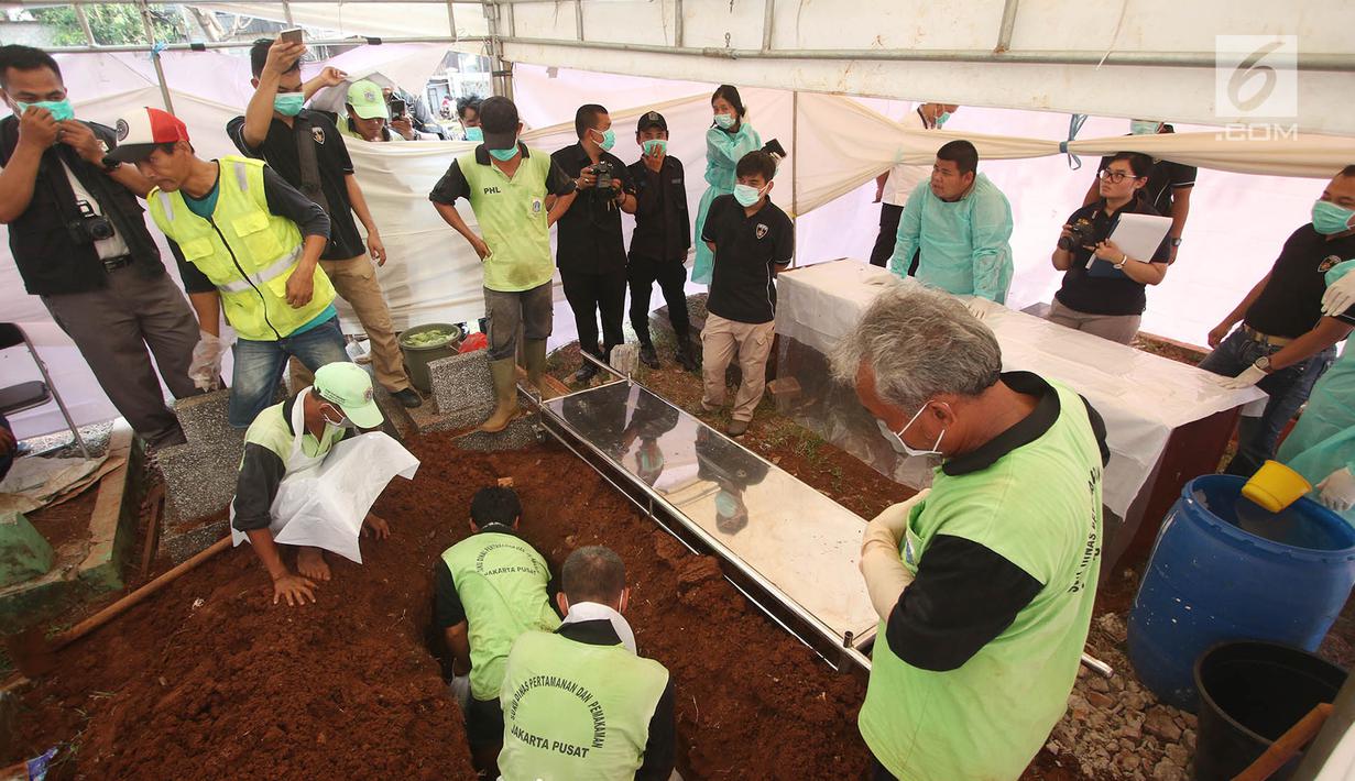 Petugas mengangkat jasad Abi Qowi Suparto (20), yang diduga mencuri vape senilai 1,6 juta, saat proses pembongkaran di TPU Karet, Jakarta Pusat, Selasa (19/9). Pembongkaran dilakukan untuk mengetahui penyebab kematian Abi. (Liputan6.com/Immanuel Antonius)