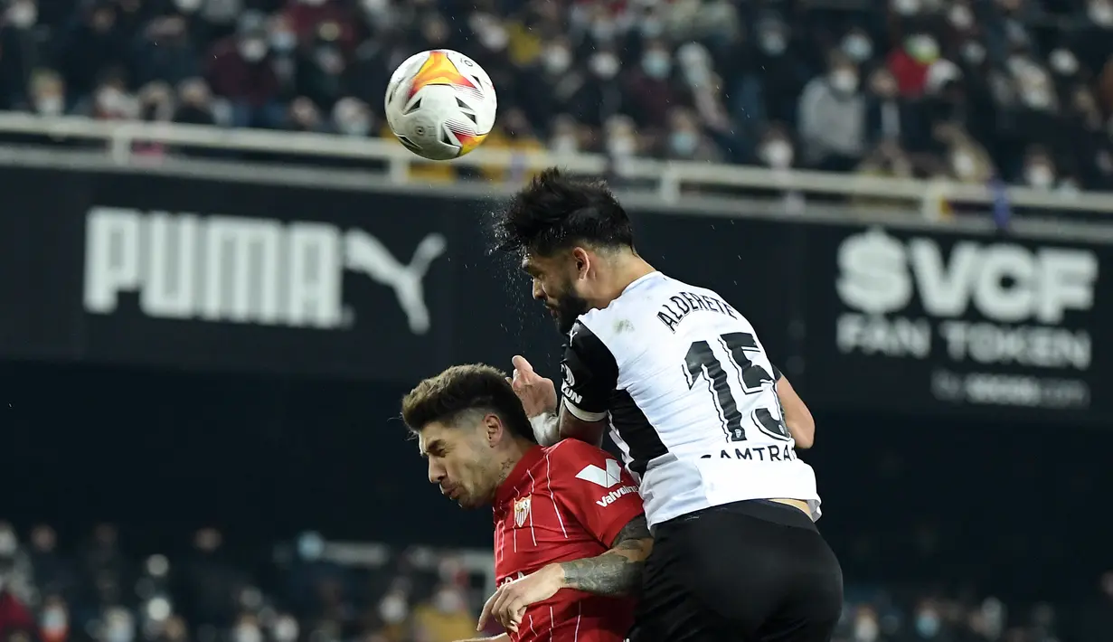Bek Sevilla, Gonzalo Montiel berebut bola udara dengan bek Valencia, Omar Alderete selama pertandingan La Liga Spanyol di stadion Mestalla di Valencia (20/1/2022).  Sevilla tetap berada di urutan dua klasemen sementara dengan koleksi 45 poin. (AFP/Jose Jordan)